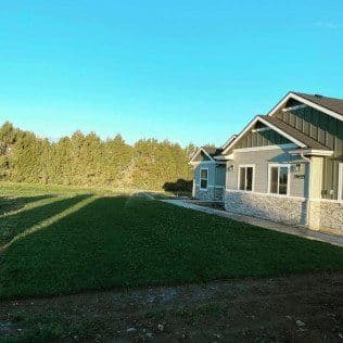 Modern home with green lawn and trees under a clear blue sky in the background.