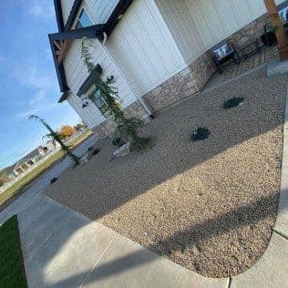 Modern house landscaping with rock garden, small trees, and neat stone pathway.
